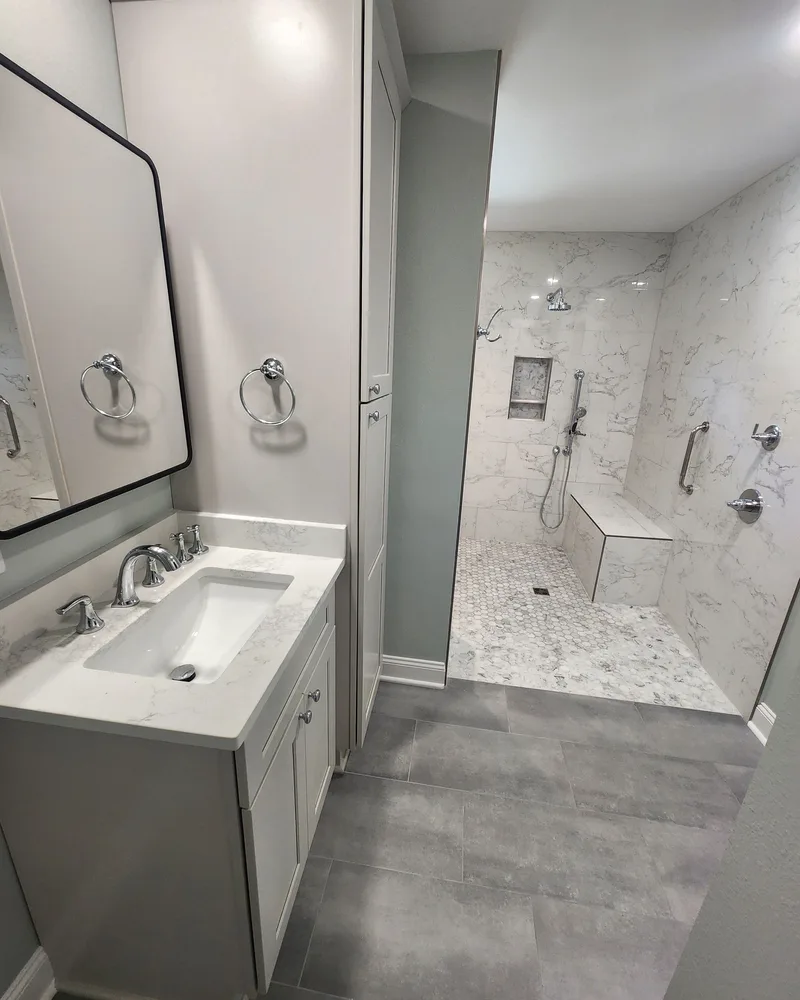 Bathroom remodel with a white vanity, a black-framed mirror and a tiled shower beyond