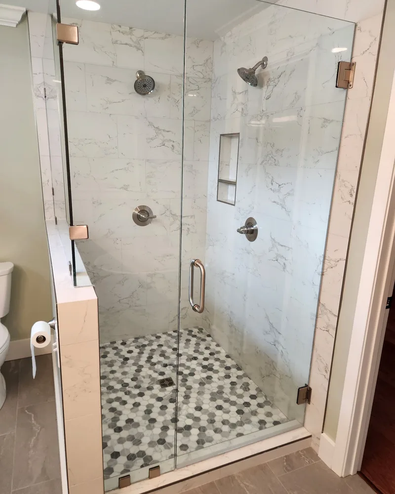 Glass shower with white marble-look walls and a pebble mosaic floor