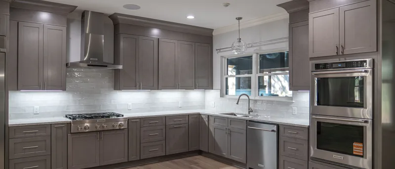 Kitchen remodel with gray shaker cabinets, a stainless hood and white subway tile