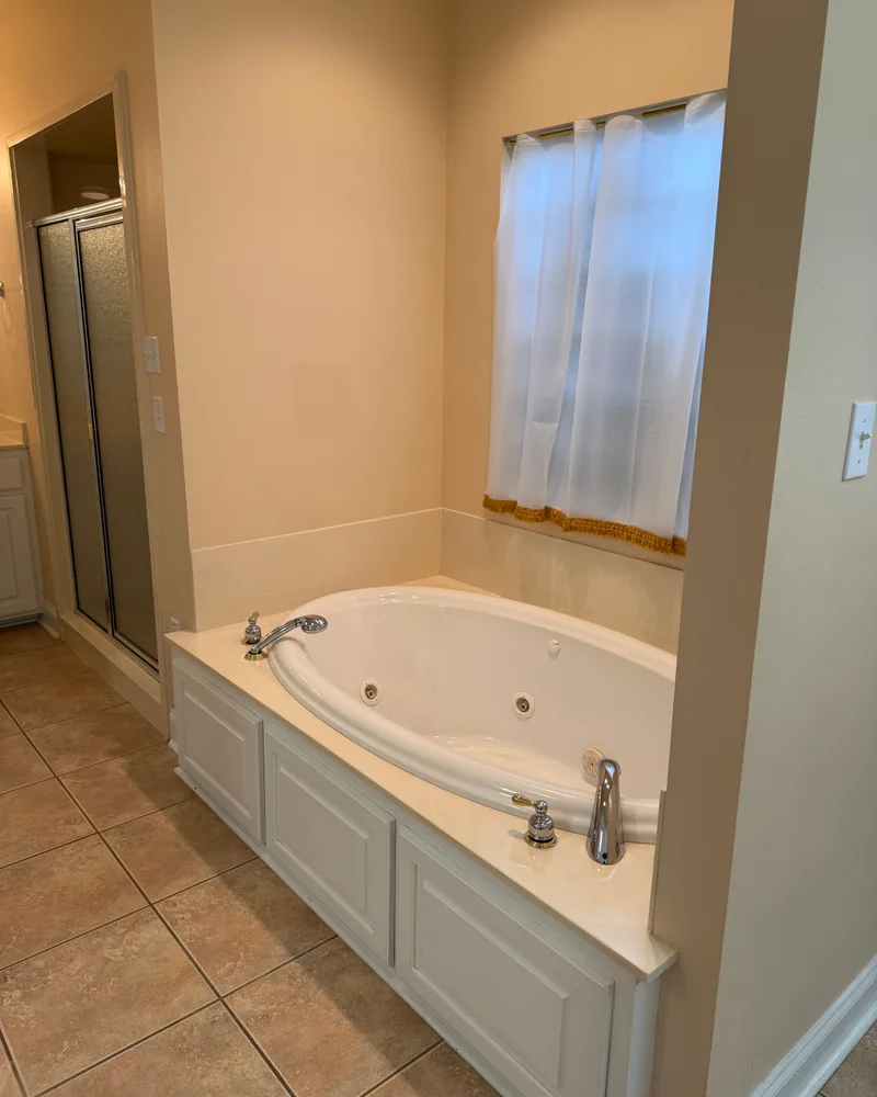 Baton Rouge master bathroom remodel, before: a beige jetted garden tub under the window