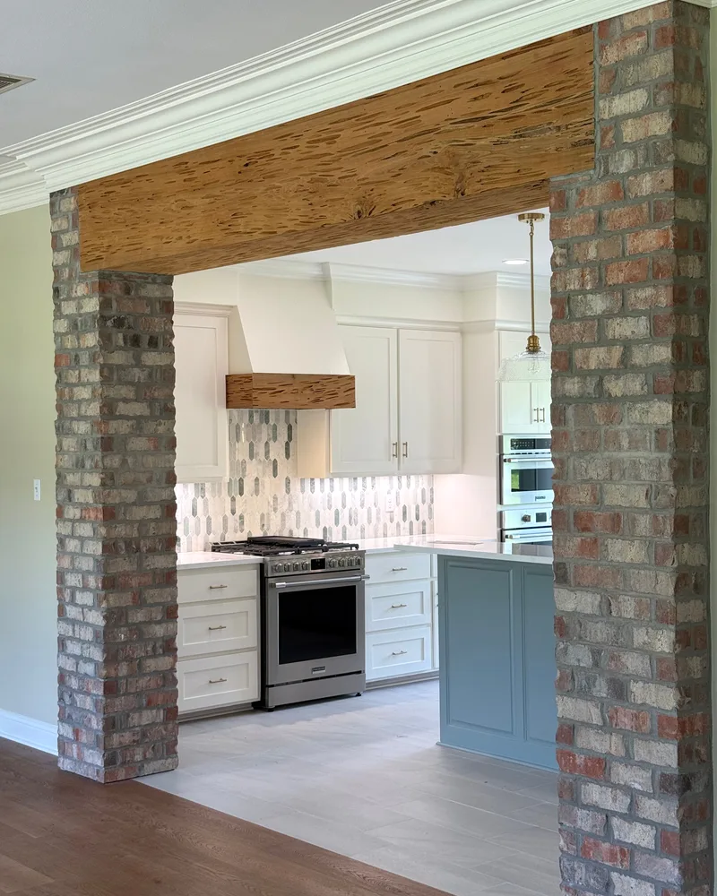 Opened brick archway framing a remodeled kitchen