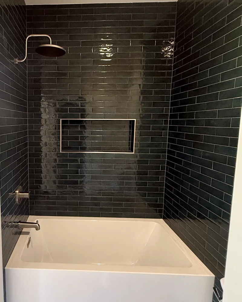 Tub and shower after the remodel Tub and shower remodel, after: a new tub with a black subway tile surround and a rain shower head