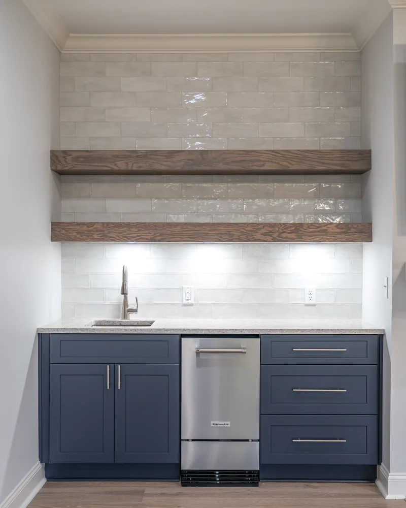 Wet bar with navy cabinets, a beverage fridge and floating wood shelves