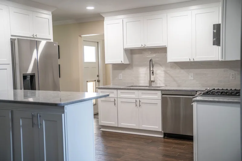 Bright finished kitchen in a Baton Rouge home with white shaker cabinets, a gray island, quartz counters and wood-look flooring